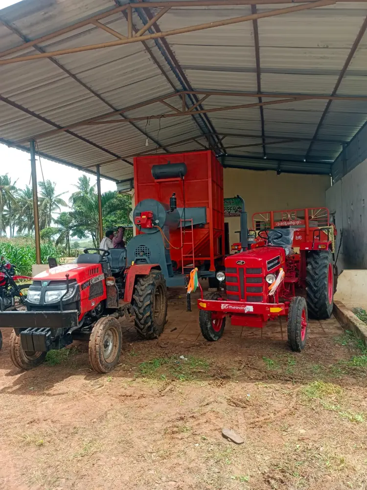Shomas mobile grain dryer at a farm shed with two tractors